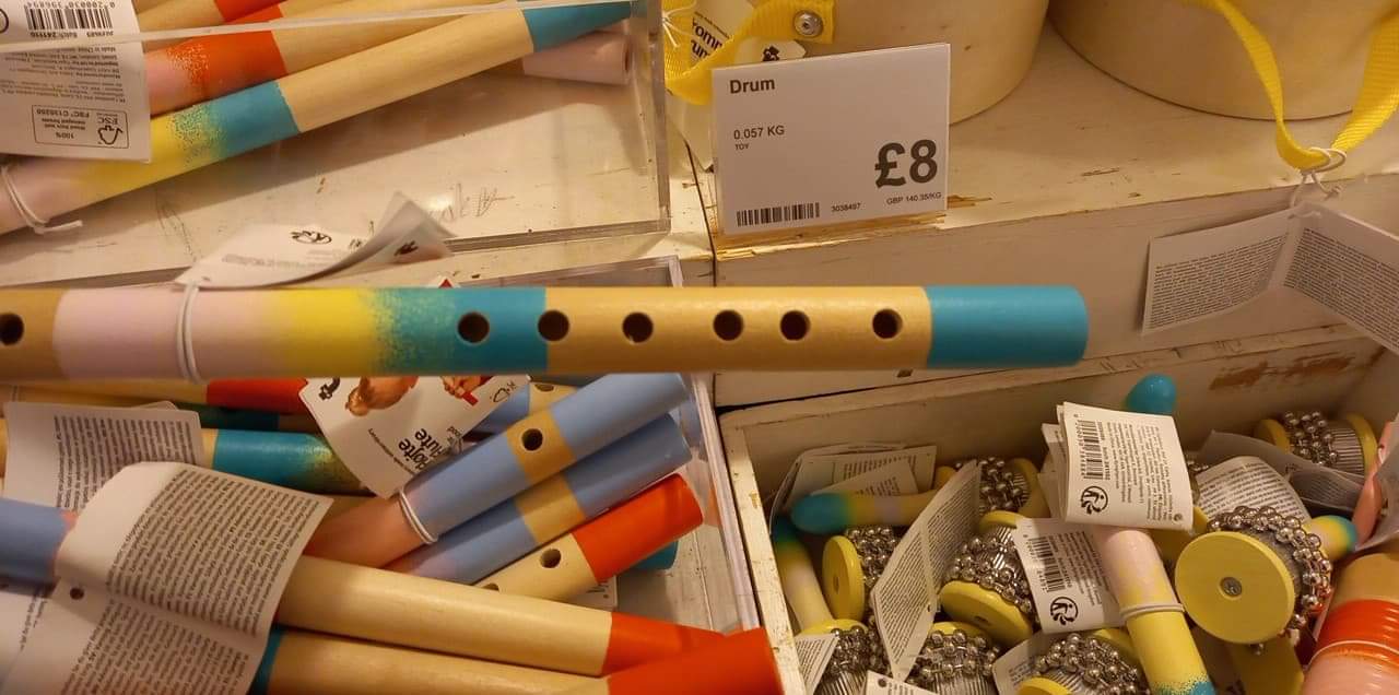 A rainbow coloured flute held above a box of colourful maracas