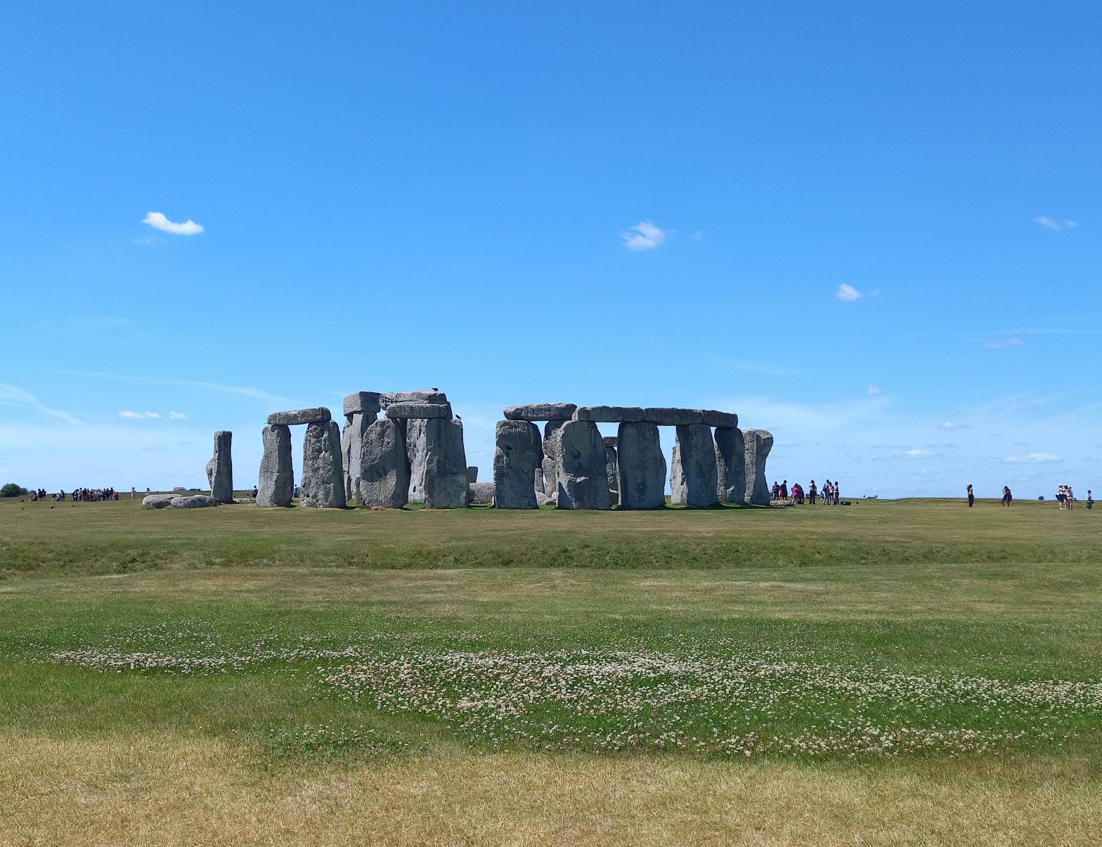 A picture of Stonehenge, a series of standing stones on a grassy background, under a sunny sky