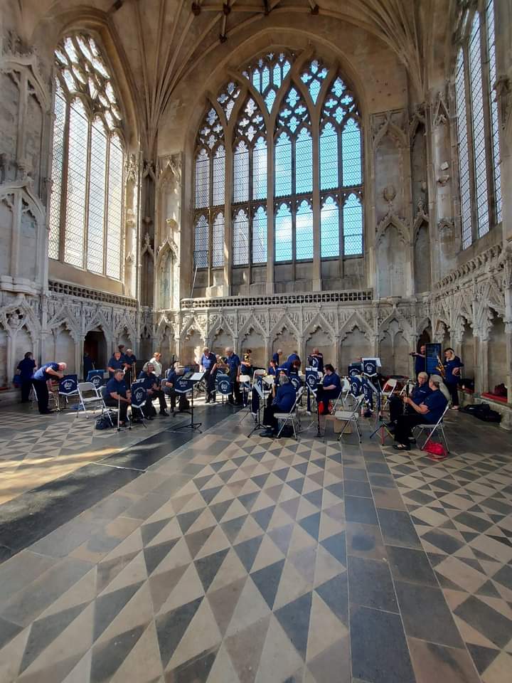 A group of muscians sitting down, wearing purple tops and black trousers, in Ely Cathedral