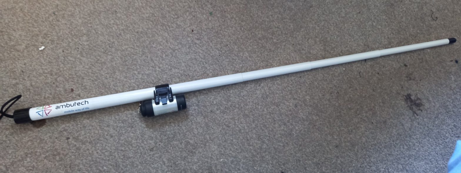 A picture of a white signal cane with black and silver torch light attached near the top on a grey background