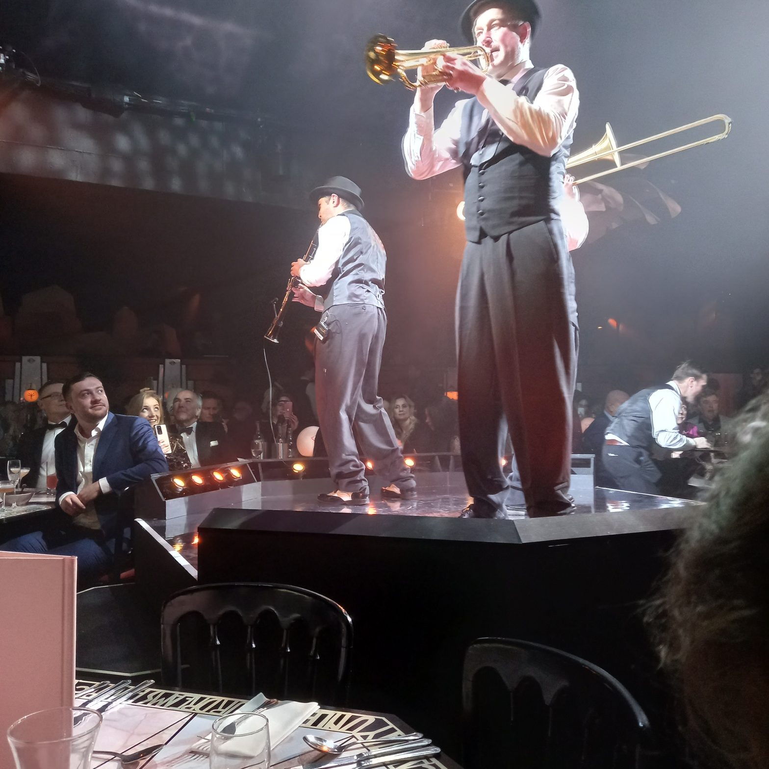 Three musicians on a stage, playing the clarinet, trumpet and trombone