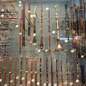 A wall of clarinets standing up, in a glass display case. 